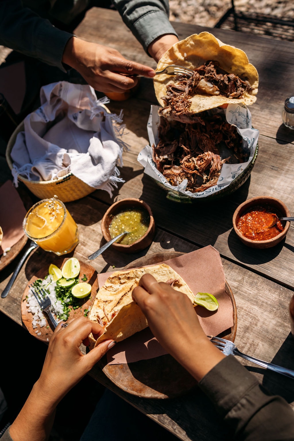 Barbacoa deshebrada y blandos de barbacoa servidos en la mesa, con salsas y guarniciones.